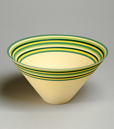 Bowl with a wide rim tapering down into a narrow base. It is yellow, the rim is decorated with stripes going around the circumference in yellow, green and blue