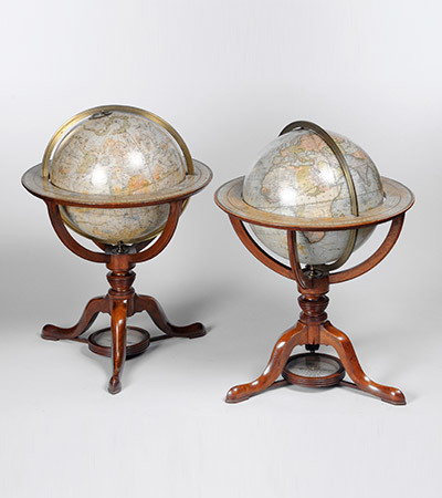 Two large globes of the Earth with wooden bases with three legs.