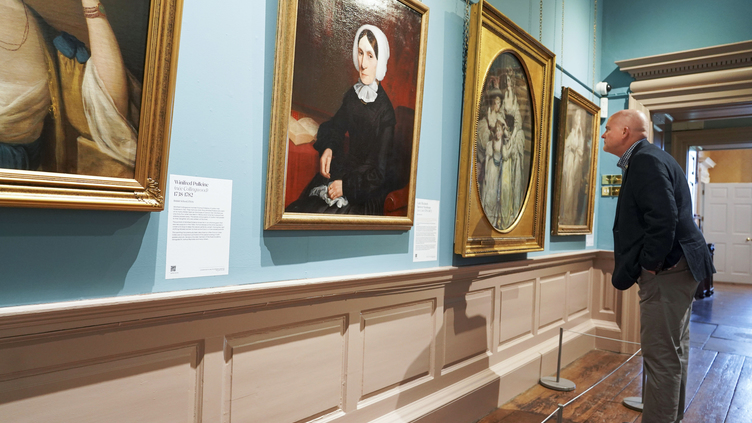 A man looking at paintings on a wall