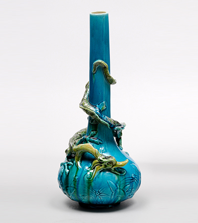Blue vase with tall thin neck and short, round body. A yellow dragon coils around with its tail around the neck and its head around the body.