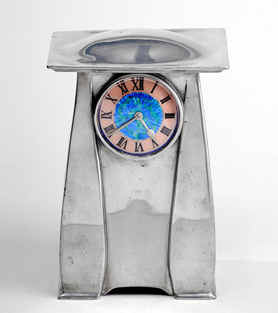 Silver clock in a rough rectangular shape. The face of the clock is at the top, with a blue centre and pink rim. The clock numbers are in black Roman numerals.