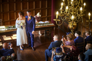 A bride and groom standing at the top of the aisle with their guests looking on