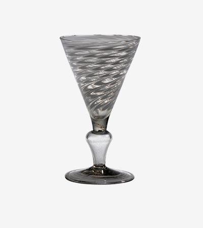 Wine glass with a short stem and triangular shaped container for the wine, tapering to a point thinner than the stem it sits on. It has swirly grey designs reminiscent of water.