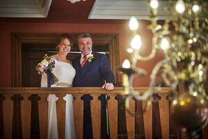 The bride and groom on a wooden balcony looking down at The Ballroom.