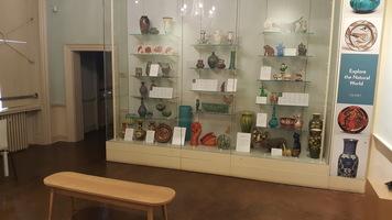 Ceramics Gallery. Displays of ceramic objects such as jars and vases and a bench in the middle of the floor.