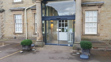 Entrance to the Hall showing glass automatic sliding doors, leading into a porch with a white automatic door which opens outwards.