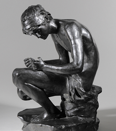 Silver sculpture of a Greek man sitting on a rock, looking down at his hands as if lost in thought