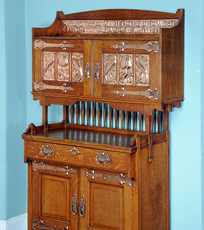 Cabinet with two parts, the bottom part is on the floor and has two cupboards with a draw on the top. There is then a shelf and the second part is build over that on legs. It has two cupboards and a shelf right at the top.