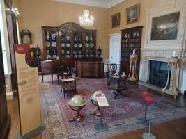 Library. Bookcases around the room and a cabinet with china plates. A writing desk and two large globes on the floor.