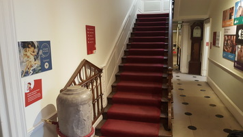 Stairs to floor one. Red carpet with handrail on the right.