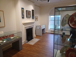 De Morgan Gallery showing displays of plates, tiles and an ornate period fireplace